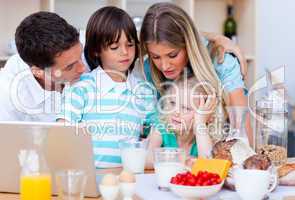 Happy family using laptop during the breakfast