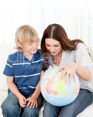 Interested child looking at a terrestrial globe with his mother