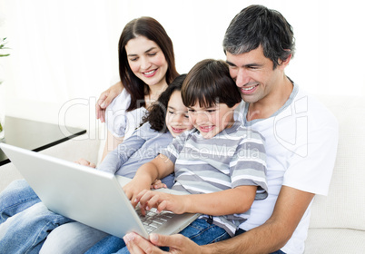 Glad family using a laptop sitting on sofa