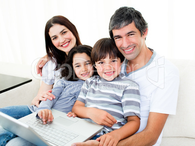 Happy family using a laptop sitting on sofa