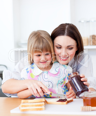 Smiling mother helping her daughter prepare the breakfast