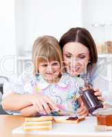 Smiling mother helping her daughter prepare the breakfast