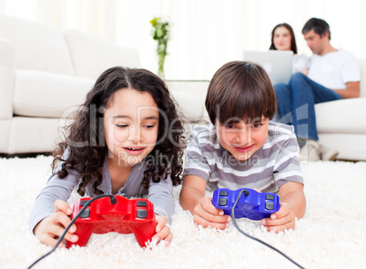 Cute siblings playing video games laying down on the floor