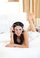 Smiling woman lying down on bed listening music