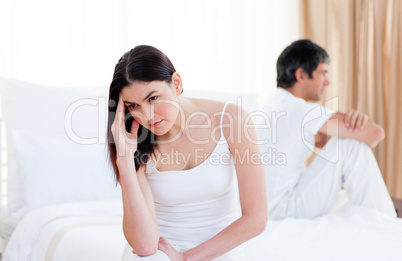 Angry couple having an argument sitting on bed