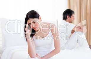 Angry couple having an argument sitting on bed