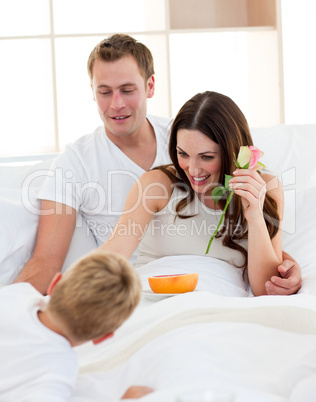 Adorable little boy having fun with his parents in the bedroom