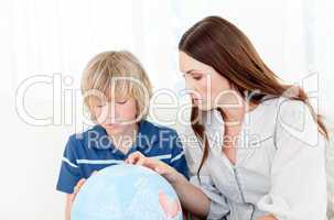 Captivated child looking at a terrestrial globe with his mother