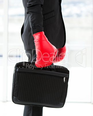 Close-up of a businessman holding a briefcase with boxing gloves