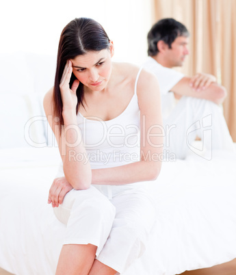 Upset couple having an argument sitting on bed