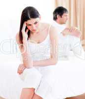 Upset couple having an argument sitting on bed