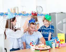 Delighted man celebrating his birthday with his wife and his chi