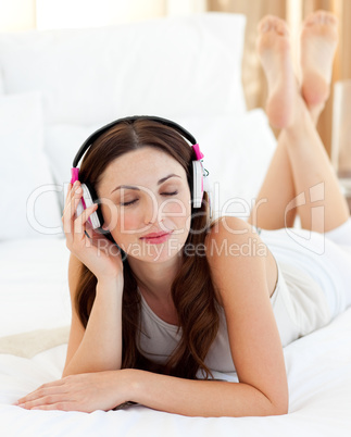 Relaxed woman lying down on bed listening music