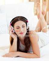 Relaxed woman lying down on bed listening music