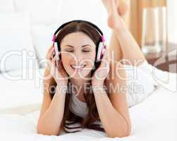 Beautiful woman lying down on bed listening music
