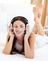Attractive woman lying down on bed listening music