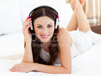 Charming woman lying down on bed listening music
