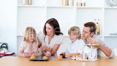 Cheerful family eating muffins in the kitchen