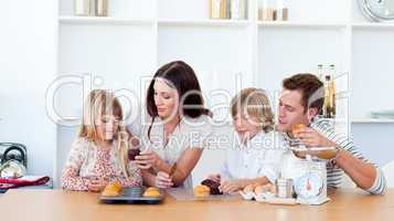 Cheerful family eating muffins in the kitchen
