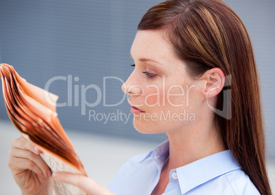 Serious businesswoman reading newspaper