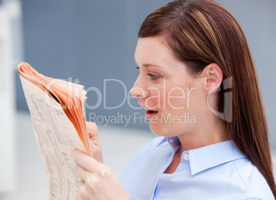 Surprised businesswoman reading newspaper