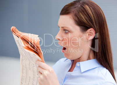Astonished businesswoman reading newspaper