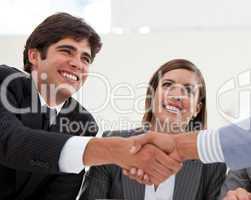 Smiling businessman and his colleague closing a deal with a part