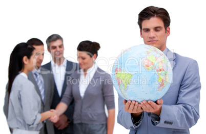 Handsome business man and his team looking at a terrestrial glob