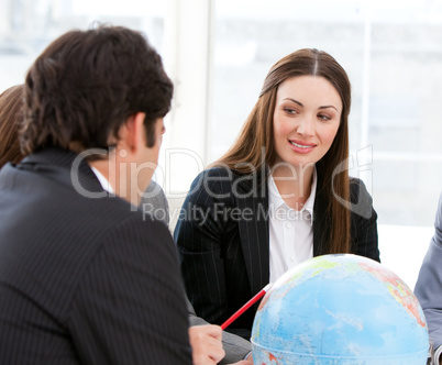 Confident businessteam looking at a terrestrial globe