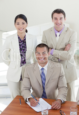 Young confident manager and his team smiling at the camera