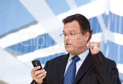 Businessman Looking at Cell Phone Clinches His Fist in Joy