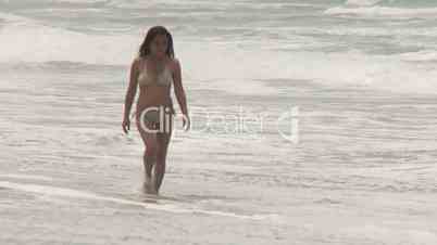 Frau im Bikini geht am Strand