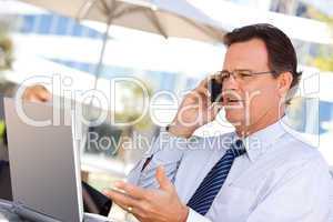 Businessman Talking on Cell Phone Using Laptop