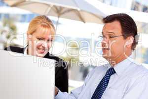 Businessman and Female Colleague Using Loptop Outdoors