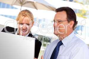 Businessman and Female Colleague Using Loptop Outdoors
