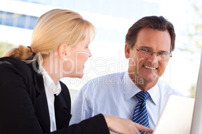 Businessman and Female Colleague Using Loptop Outdoors