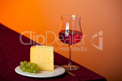 Stück Käse, eine Traube und Rotwein