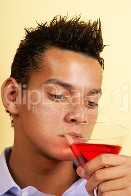 Young man drinking red cocktail