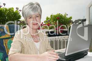 Frau mit Laptop auf Balkon
