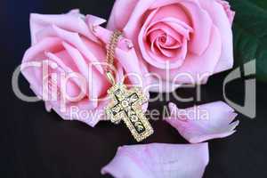 Kreuzkette und rosa Rosen