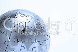 Metal puzzle globe isolated on white background, close-up in blue light