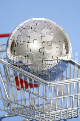 Metal puzzle globe with shopping cart on blue background