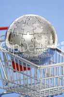 Metal puzzle globe with shopping cart on blue background