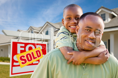 Father with Son In Front of Real Estate Sign and Home