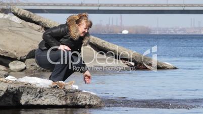woman plays water on river bank.