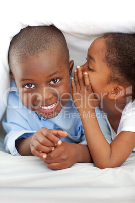 Adorable little girl whispering something to her brother