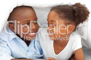 Portrait of laughing siblings lying down on bed