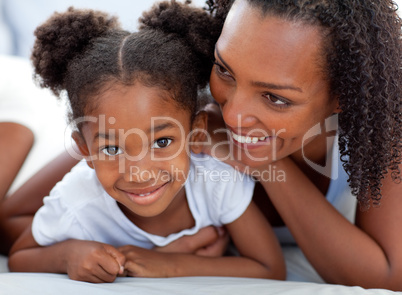 Attentive woman and her daughter relaxing lying down on bed