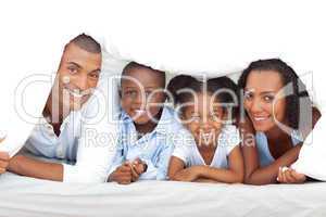 Merry family having fun lying down on bed