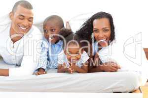 Lively family having fun lying down on bed